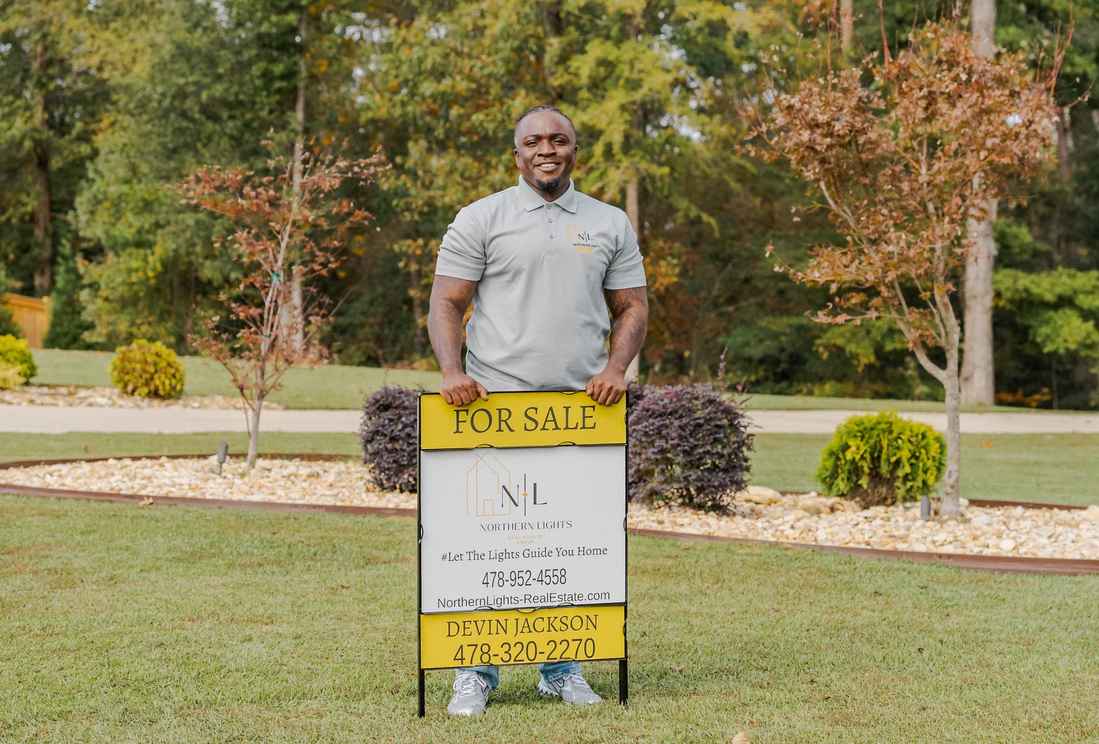 Northern Lights real estate agent outdoors with a branded for-sale sign
